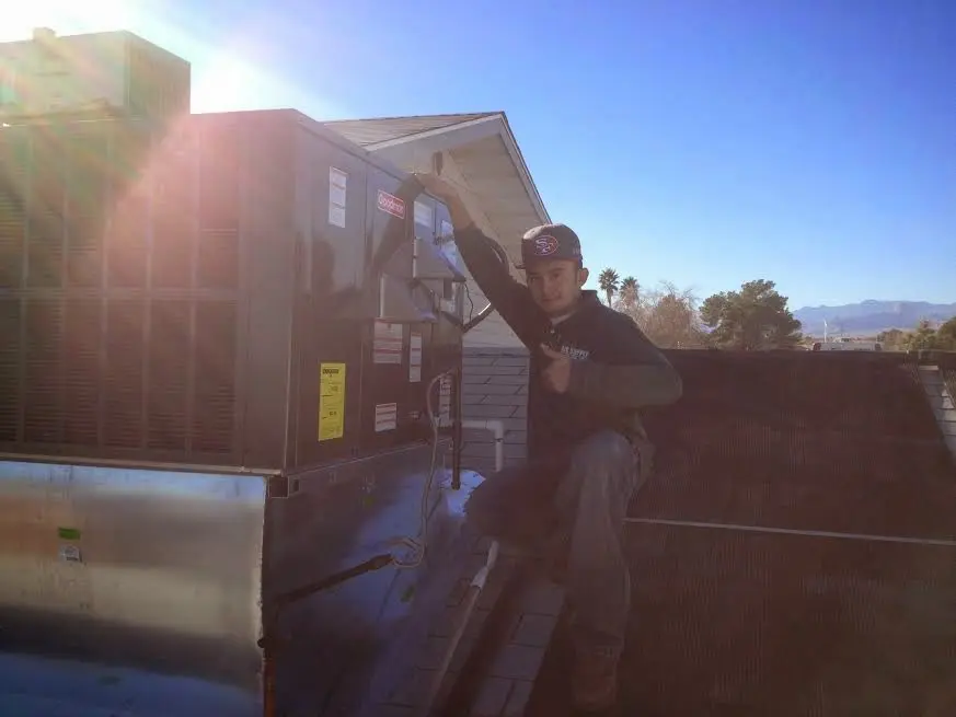 HVAC technician performing AC Tune-Up on a rooftop unit in San Benito