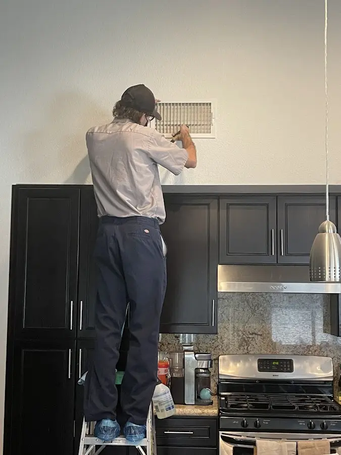 Technician inspecting an air vent during HVAC service in San Benito